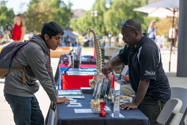 Student speaking with a representative at a table at a campus fair